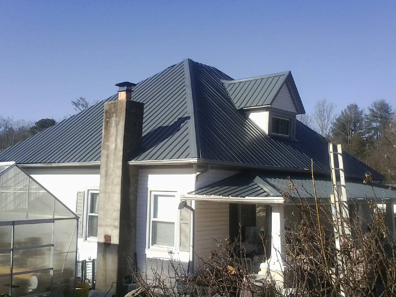 Dark blue standing seam metal roof on a white farmhouse with dormer — Slate & Tile Roof Repair by Roofing Brothers in Paxinos