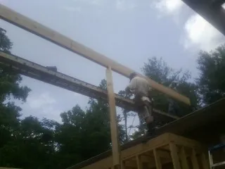Carpenter setting a ridge beam over a new addition frame — Ice Dam Removal by Roofing Brothers in Paxinos