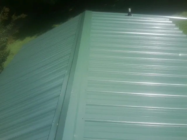 New green metal panels meeting at the ridge of a roof — Flat Roof Repair work by our crew in Paxinos
