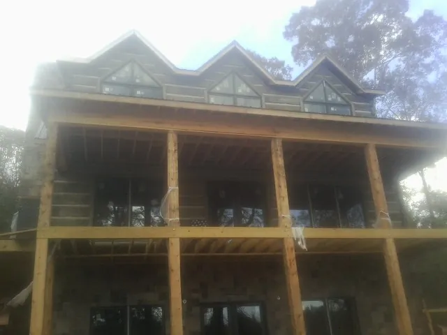 Dormers and porch framing on a large log home under construction — Roof Coating work by our crew in Paxinos