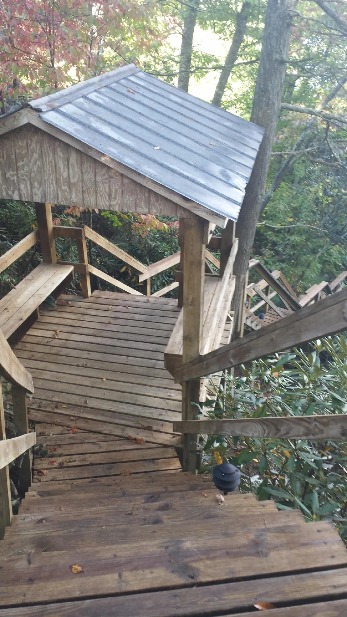Metal roofed shelter over wooden steps on a wooded walkway — Skylight Repair & Installation work by our crew in Paxinos