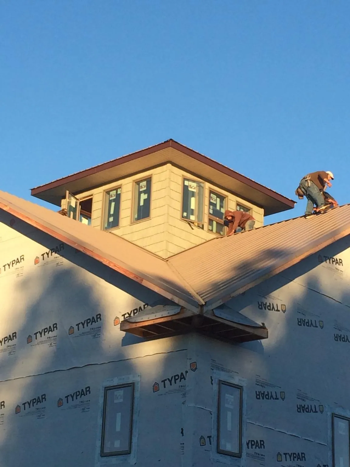 Roofers working around a rooftop cupola on a new metal roof at sunset — Roof Waterproofing in Paxinos by Roofing Brothers